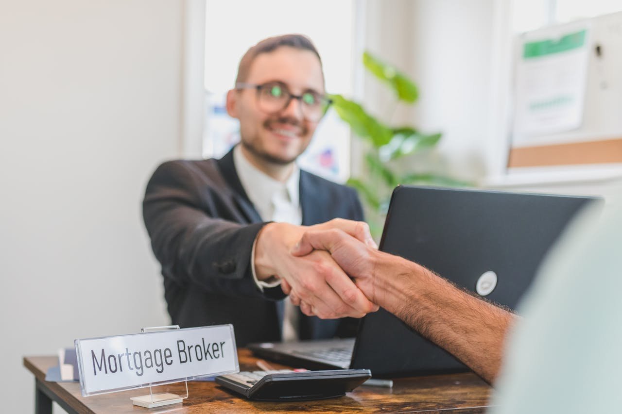 our-story Mortgage broker and client sealing a deal with a handshake in a bright, modern office.