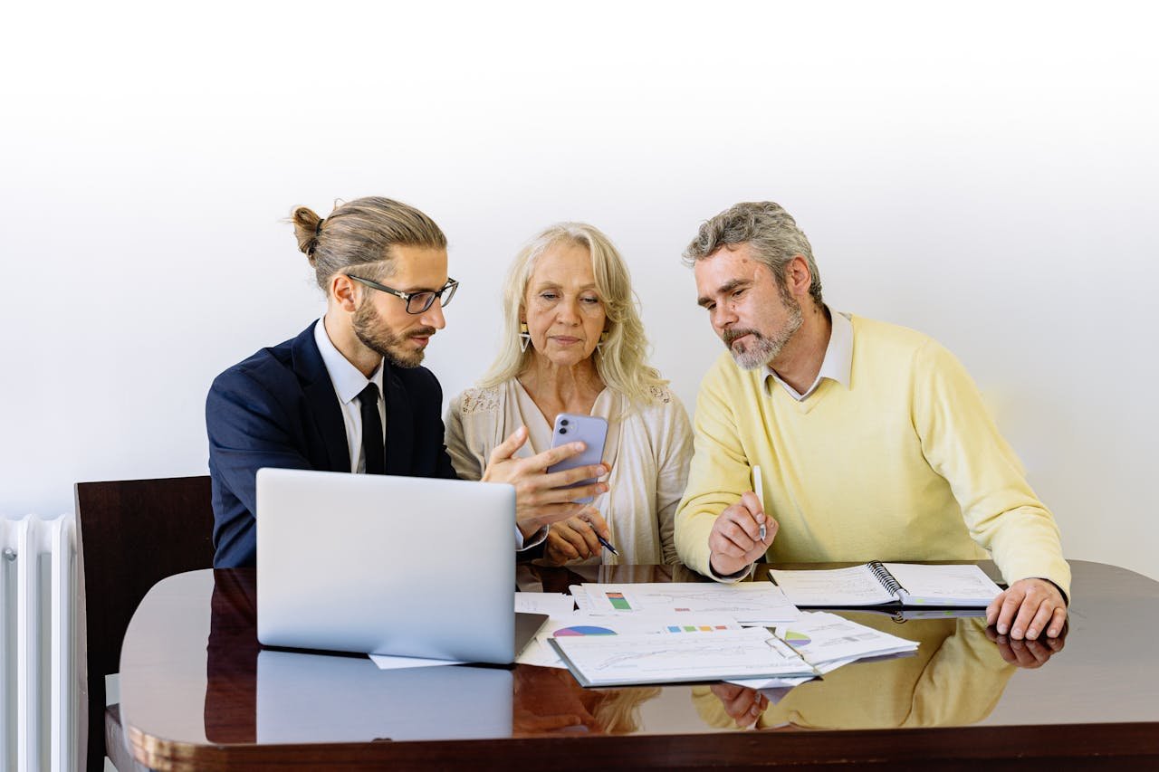 services-03 Three individuals collaborating on financial documents during a business meeting.